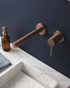 Blutide wall-mounted basin mixer and spout on a navy wall above a marble basin