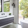 Modern bathroom with a dark vanity, freestanding bath and garden outlook