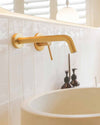 Blutide brushed brass wall-mounted basin mixer over a stone basin