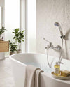Blutide wall-mounted bath mixer with hand shower beside a freestanding bath