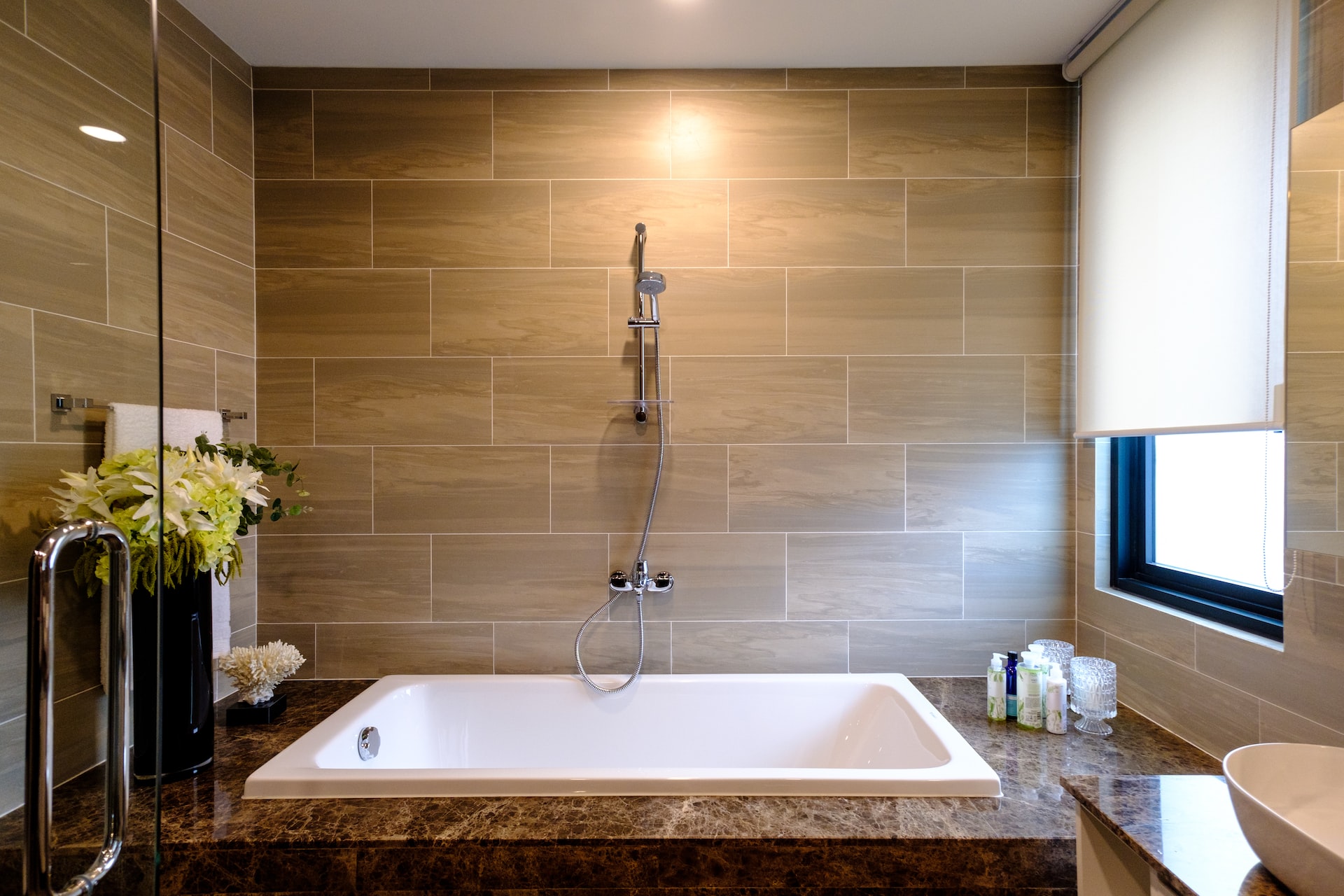An elegant tiled bathroom featuring a built-in tub and natural colours